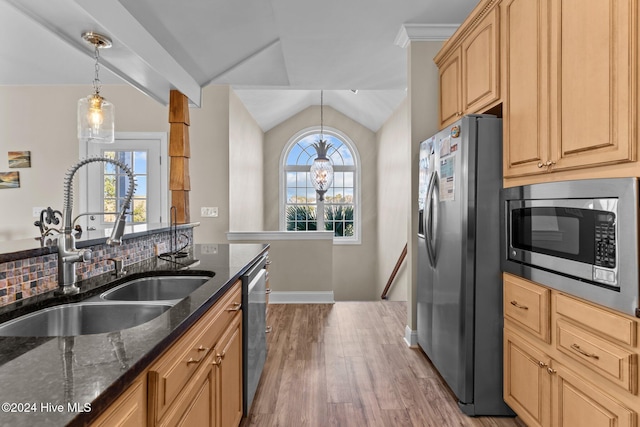 kitchen with appliances with stainless steel finishes, dark stone countertops, a sink, and a healthy amount of sunlight