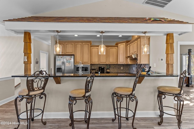 kitchen featuring a breakfast bar area, stainless steel appliances, visible vents, backsplash, and under cabinet range hood