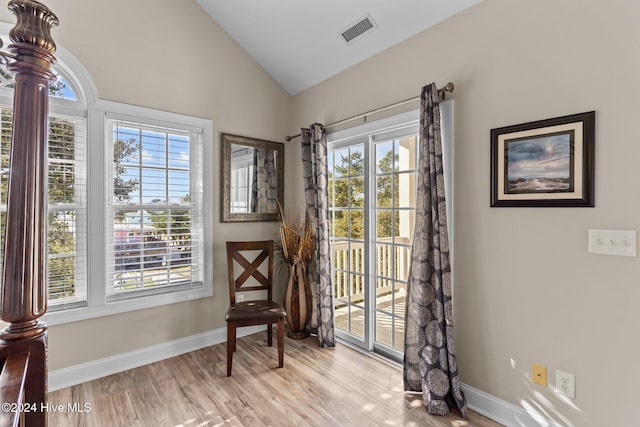 living area featuring vaulted ceiling, wood finished floors, visible vents, and baseboards