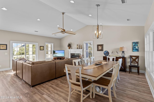 dining space with light hardwood / wood-style flooring, ceiling fan with notable chandelier, and lofted ceiling