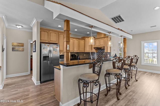 kitchen featuring a breakfast bar area, tasteful backsplash, decorative light fixtures, kitchen peninsula, and stainless steel appliances