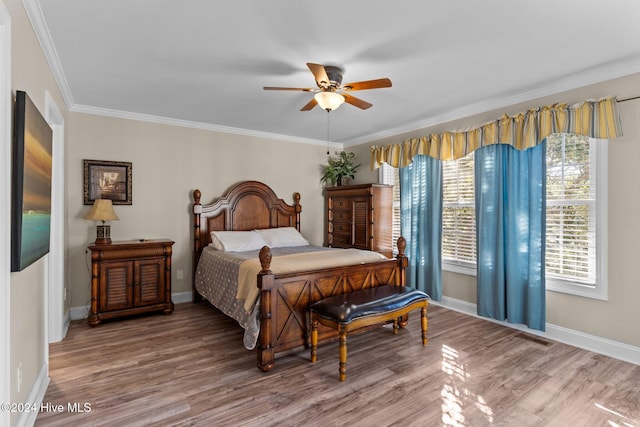 bedroom with visible vents, crown molding, baseboards, and wood finished floors