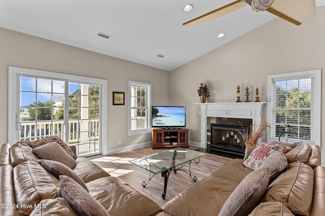 living area featuring visible vents, a high end fireplace, vaulted ceiling, wood finished floors, and baseboards