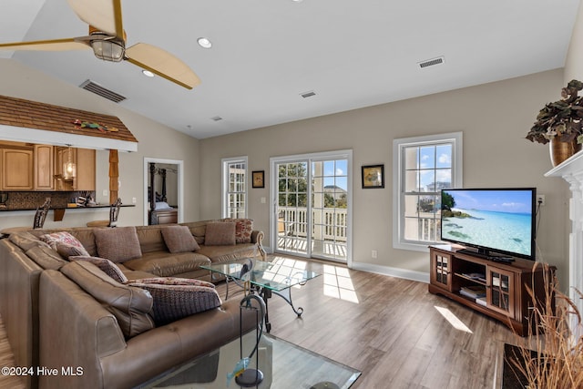 living room featuring ceiling fan, light hardwood / wood-style floors, and vaulted ceiling