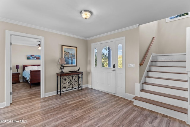 foyer entrance featuring light wood-type flooring, stairs, baseboards, and crown molding