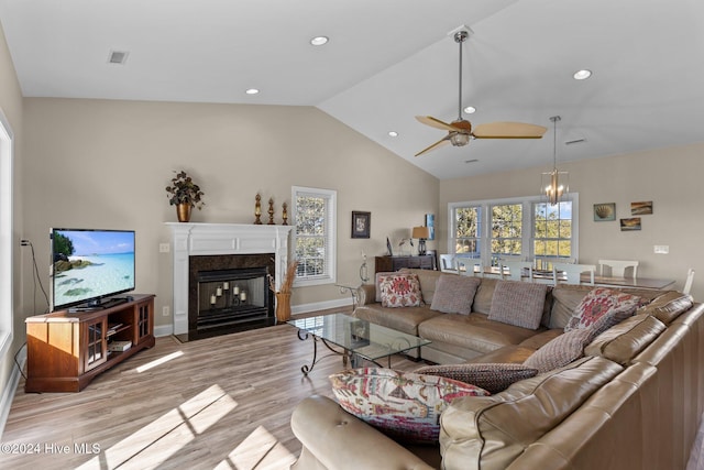 living room featuring a fireplace, light hardwood / wood-style floors, high vaulted ceiling, and ceiling fan