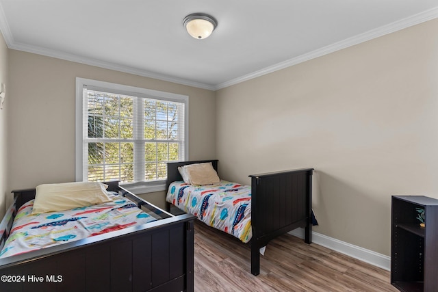 bedroom featuring crown molding, wood finished floors, and baseboards