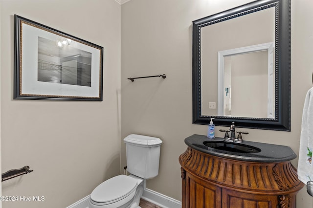 half bathroom featuring toilet, baseboards, and vanity