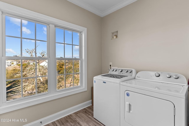 clothes washing area with laundry area, baseboards, washer and clothes dryer, ornamental molding, and wood finished floors