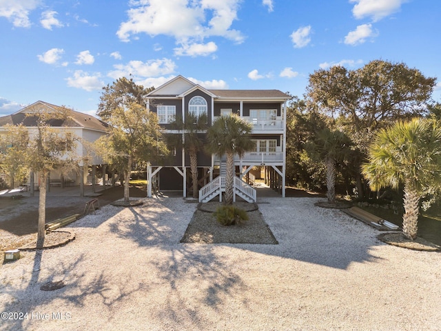 coastal home with covered porch, a carport, stairway, and a balcony