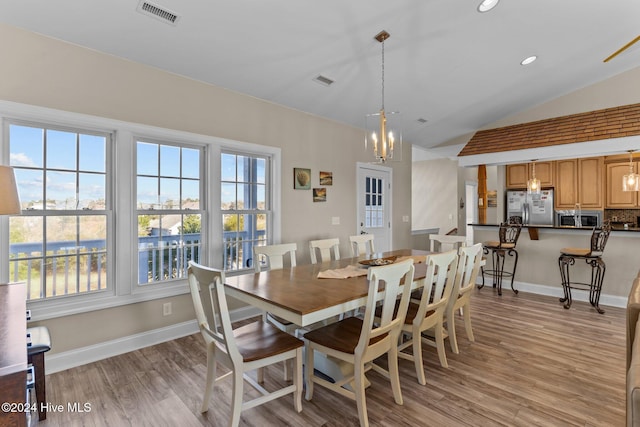 dining area with light wood-style flooring, visible vents, vaulted ceiling, and baseboards