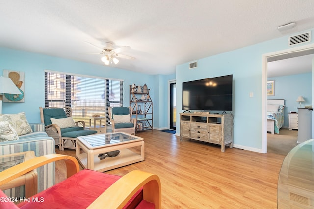 living room with hardwood / wood-style floors, ceiling fan, and a textured ceiling