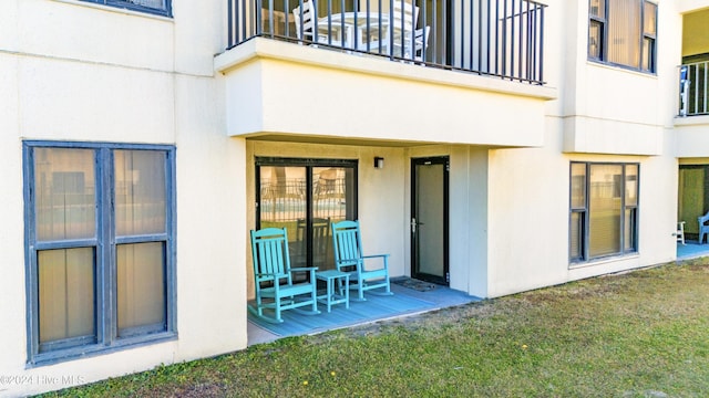 rear view of house with a lawn and a balcony