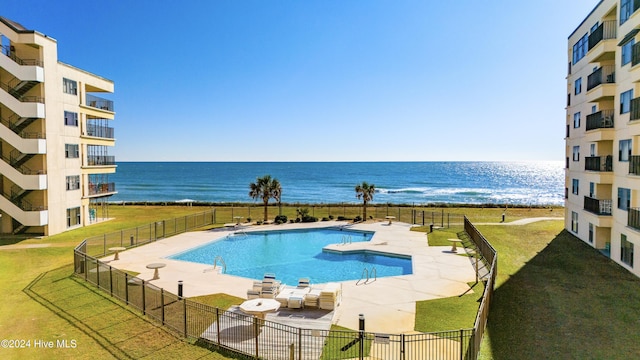 view of pool with a lawn, a water view, and a patio