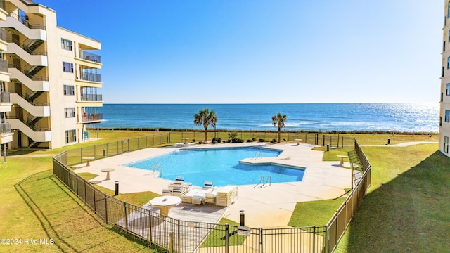 view of swimming pool with a patio, a water view, and a lawn