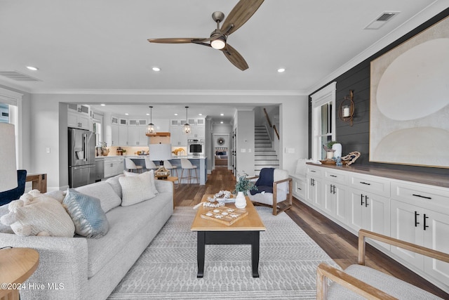 living room with dark hardwood / wood-style flooring, ceiling fan, and crown molding