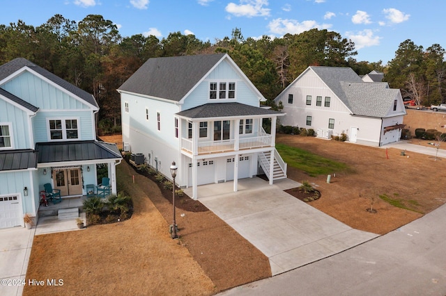 view of front of home with central air condition unit, a front yard, a porch, and a garage