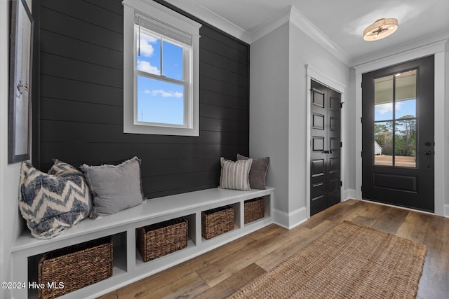 mudroom with wood-type flooring, ornamental molding, and wooden walls