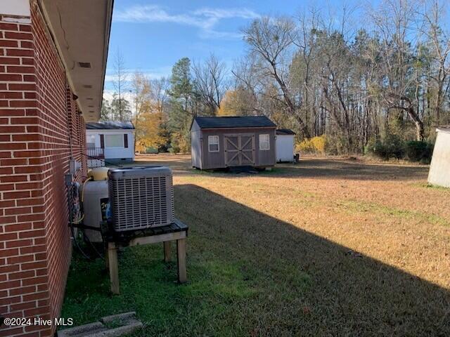 view of yard featuring cooling unit and a storage shed