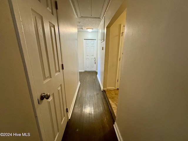 corridor with a textured ceiling, dark hardwood / wood-style floors, and ornamental molding