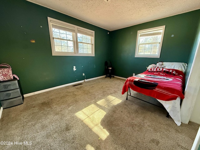 bedroom with carpet flooring, a textured ceiling, and multiple windows