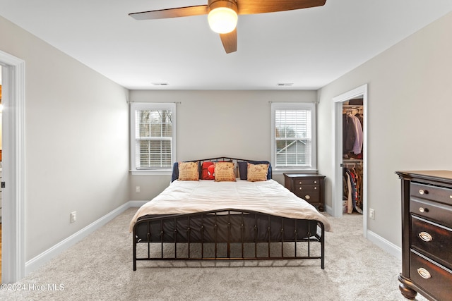 carpeted bedroom with a spacious closet, a closet, and ceiling fan