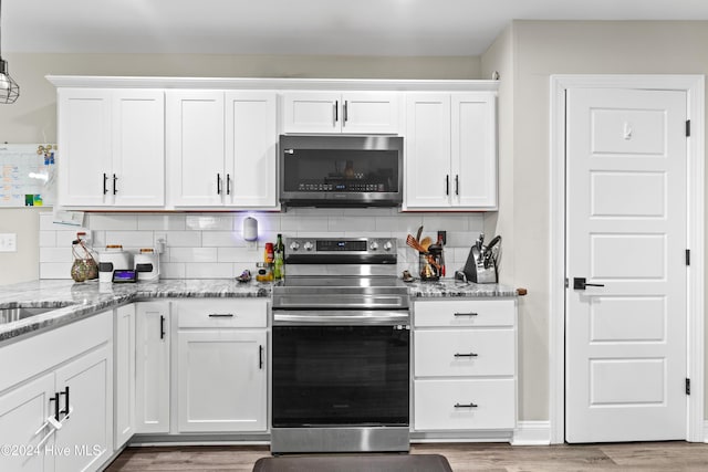 kitchen with backsplash, white cabinets, light hardwood / wood-style floors, and appliances with stainless steel finishes