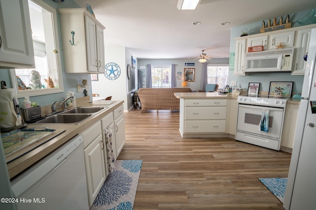 kitchen featuring kitchen peninsula, light hardwood / wood-style flooring, sink, white cabinetry, and white appliances