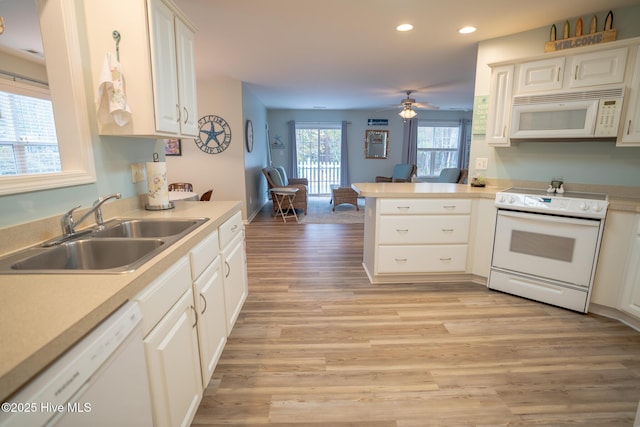 kitchen featuring white appliances, white cabinets, sink, kitchen peninsula, and light hardwood / wood-style flooring