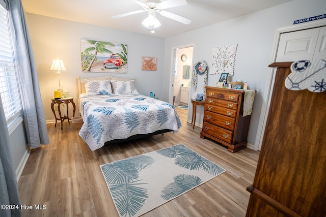 bedroom featuring light wood-type flooring, ceiling fan, and ensuite bath