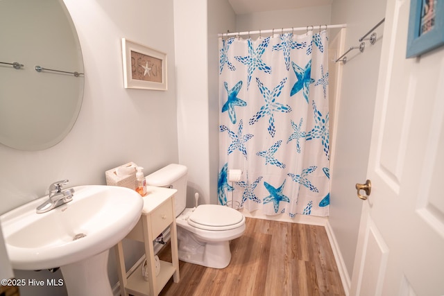 bathroom featuring a shower with curtain, hardwood / wood-style flooring, toilet, and sink