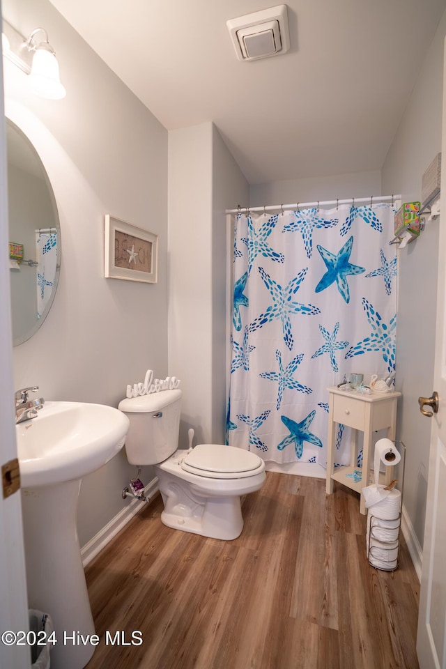 bathroom featuring curtained shower, hardwood / wood-style floors, and toilet