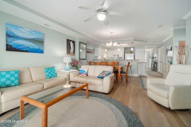 living area with ceiling fan with notable chandelier, baseboards, light wood-style floors, and crown molding