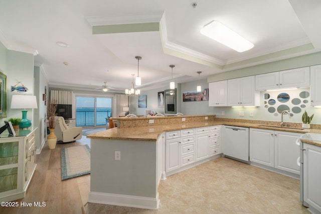 kitchen featuring a raised ceiling, open floor plan, a sink, white cabinetry, and dishwasher
