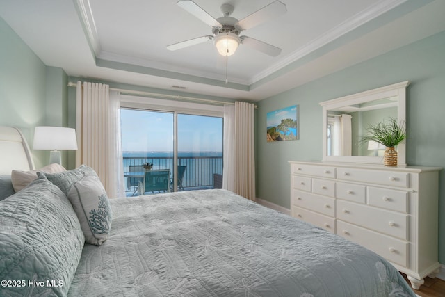 bedroom with a tray ceiling, access to outside, a water view, and ornamental molding
