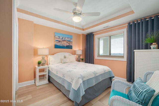 bedroom featuring baseboards, ornamental molding, a raised ceiling, visible vents, and light wood finished floors