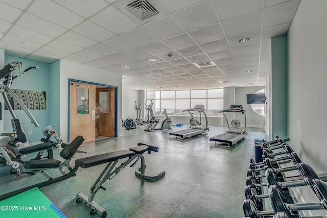 exercise room with a paneled ceiling, visible vents, and baseboards