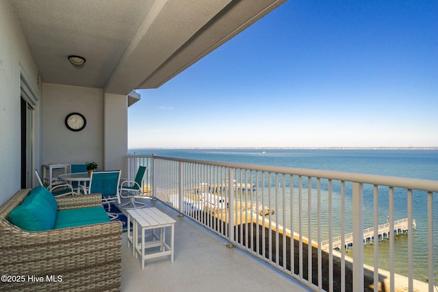balcony with outdoor dining area and a water view