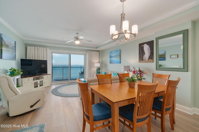 dining room featuring light wood-type flooring, ceiling fan with notable chandelier, baseboards, and ornamental molding