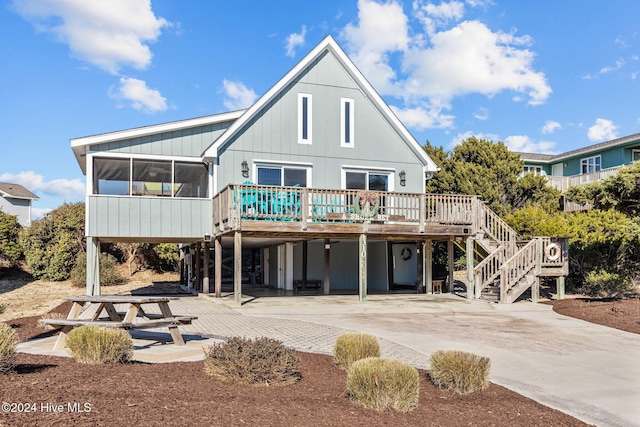 rear view of house with a wooden deck, a sunroom, and a carport