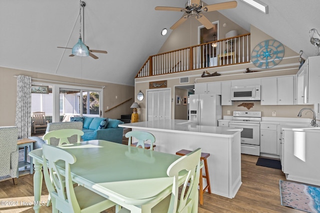 dining area with hardwood / wood-style flooring, ceiling fan, sink, and high vaulted ceiling