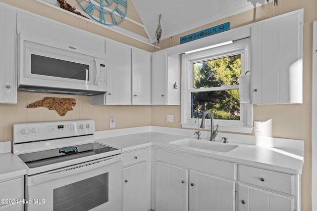 kitchen with white appliances, white cabinetry, and sink