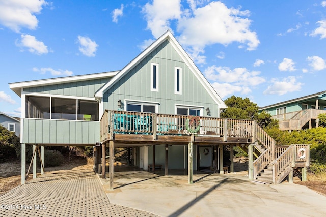 back of house featuring a wooden deck, a sunroom, and a carport