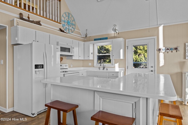 kitchen with a breakfast bar, white appliances, high vaulted ceiling, dark hardwood / wood-style floors, and white cabinetry