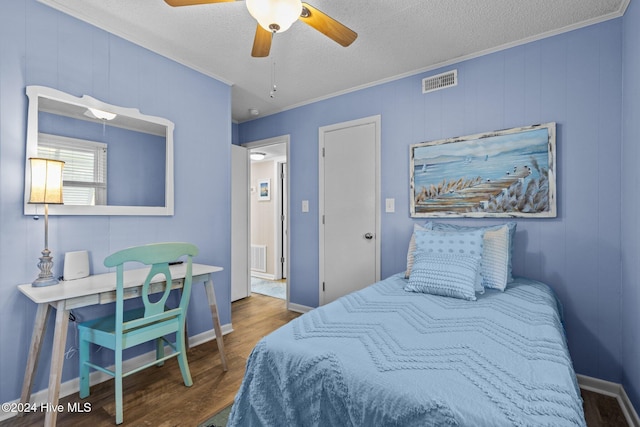 bedroom with ceiling fan, dark hardwood / wood-style flooring, ornamental molding, and a textured ceiling