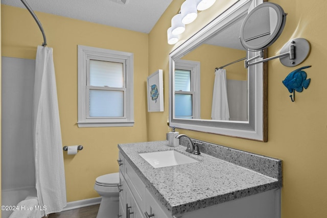 full bathroom featuring vanity, toilet, shower / bath combo with shower curtain, and a textured ceiling