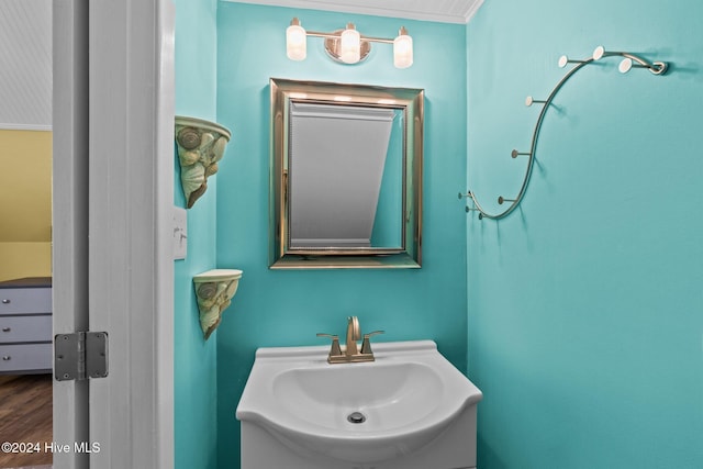 bathroom with crown molding, vanity, and wood-type flooring