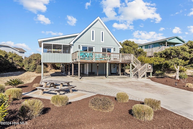 back of house featuring a sunroom, a patio area, and a wooden deck