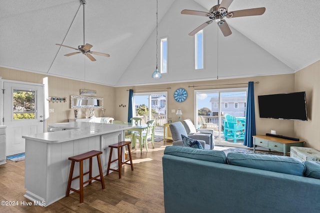 living room with wood-type flooring, high vaulted ceiling, ceiling fan, and a healthy amount of sunlight