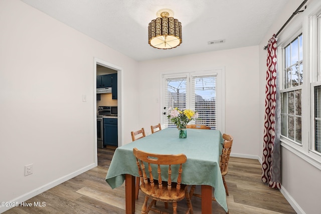 dining room with a wealth of natural light, visible vents, light wood-type flooring, and baseboards